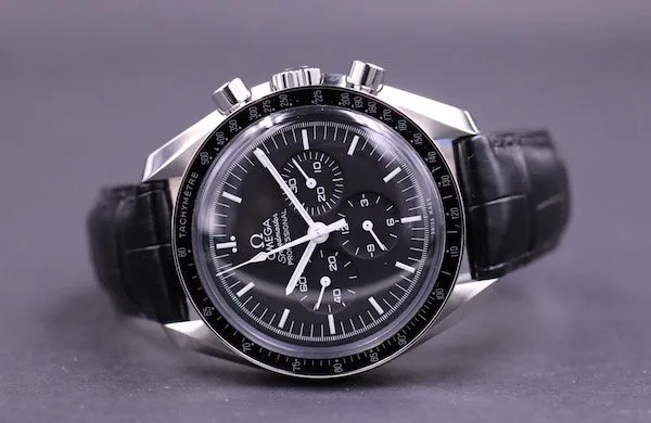 Omega Speedmaster chronograph with a black dial and black leather strap on a grey surface